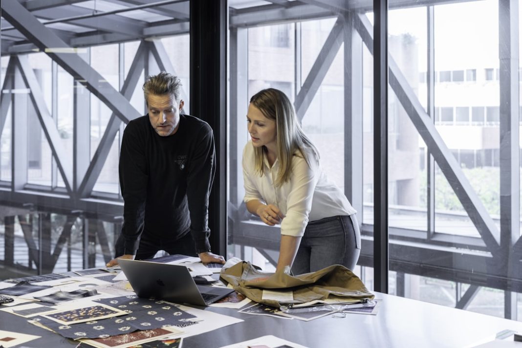 Sales professionals using sales coaching guide on laptop at corporate office